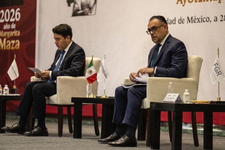 Undersecretary Arturo Medina and special prosecutor Mauricio Pazarán seated on stage at the Sept. 28, 2026 Ayotzinapa case report in Mexico City, with Gobernación and FGR flags