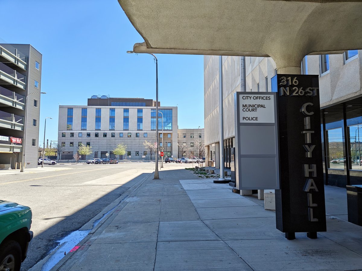 Billings City Hall entrance sign listing city offices, municipal court and police, with the Battin Federal Courthouse across the street