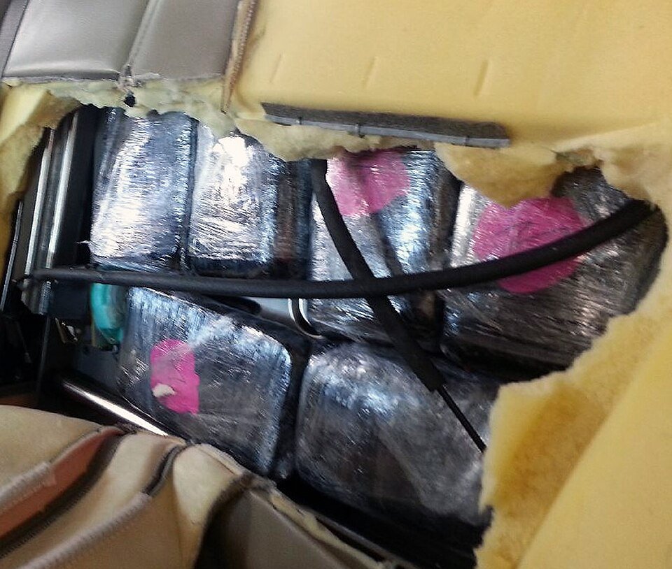 Plastic-wrapped packages of methamphetamine hidden behind the cut-open upholstery of a vehicle seat