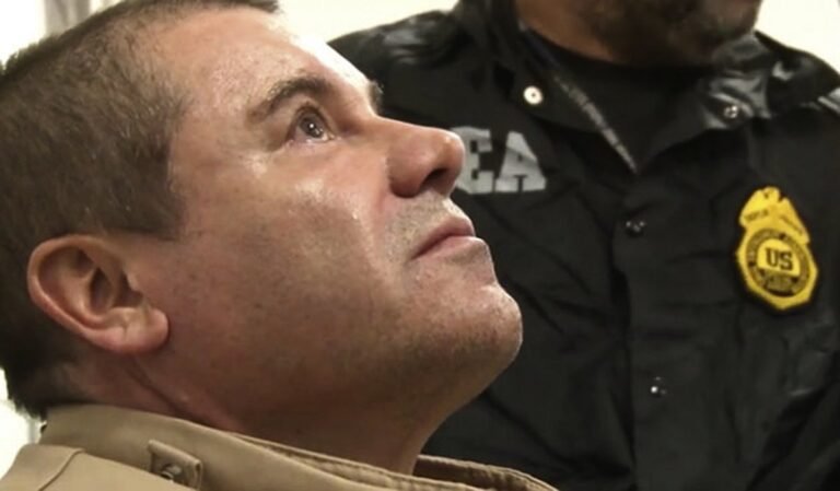 Joaquín “El Chapo” Guzmán looks up as a DEA agent stands beside him after his extradition to the United States in January 2017