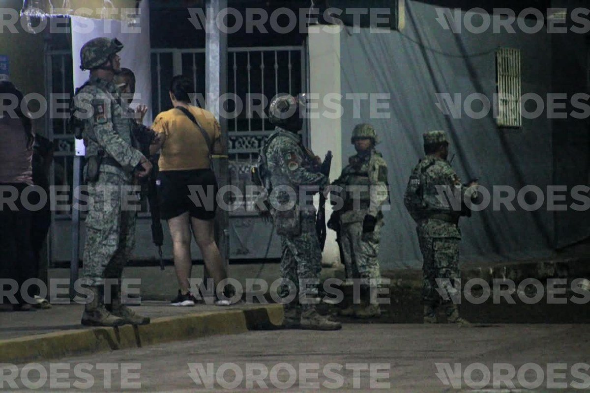Mexican soldiers stand outside a gated house in Culiacán's 5 de Febrero neighborhood as residents look on after the Sept. 29 shooting