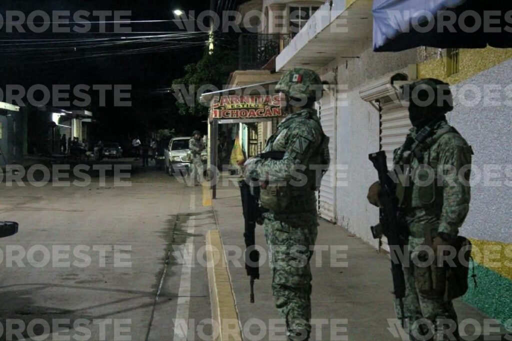 Armed Mexican Army soldiers stand guard on Juan de la Cabada street in Culiacán's 5 de Febrero neighborhood at night after the Sept. 29 shooting