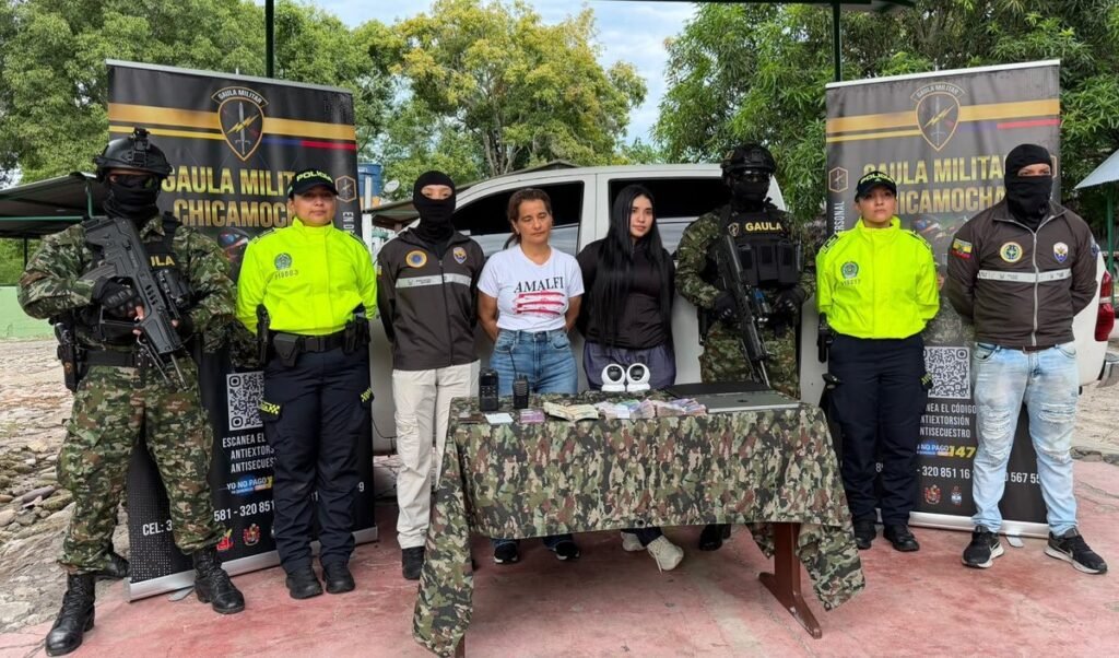 Inda Peñarrieta and Michelle Macías Peñarrieta stand between Colombian police officers, masked soldiers and Ecuadorian police behind a table of cash, radios and laptops in front of Gaula Militar Chicamocha banners