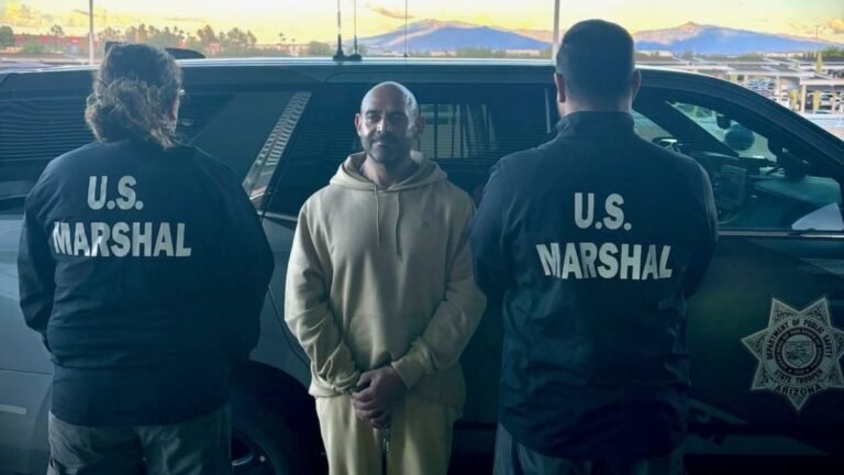 Jorge Lamadrid-Carranza stands between two U.S. Marshals beside an Arizona DPS vehicle after his return to Arizona
