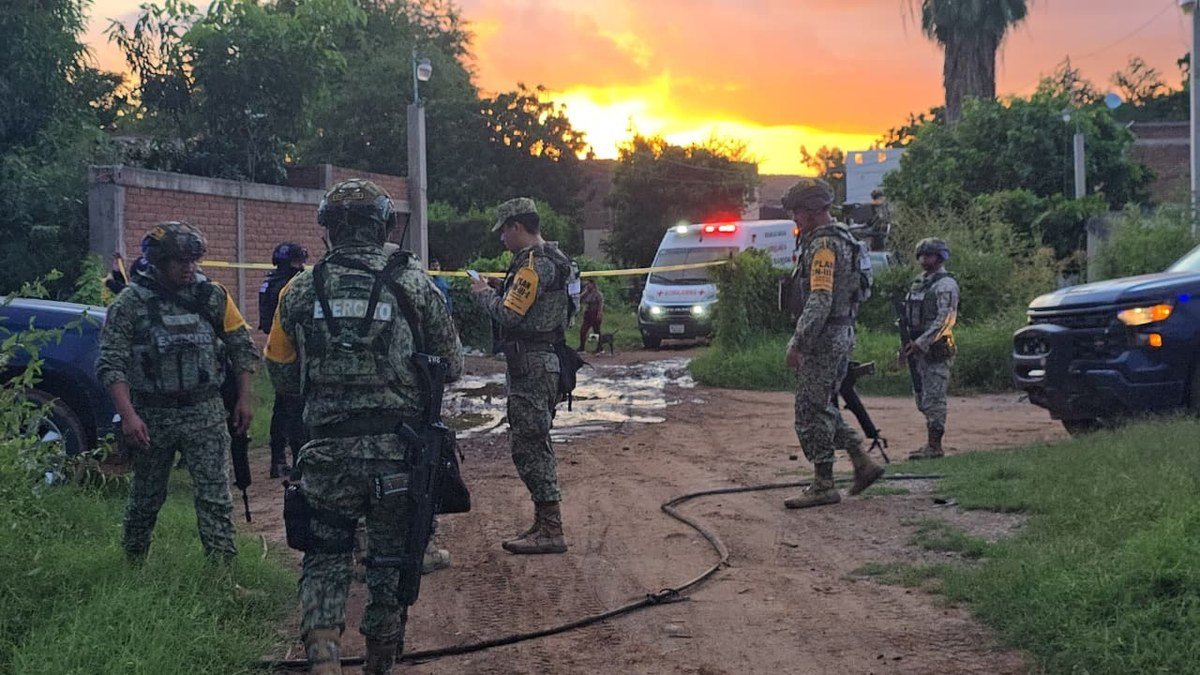 Mexican Army soldiers on a dirt road near police tape and a Red Cross ambulance at sunset in Los Mezcales, Culiacán