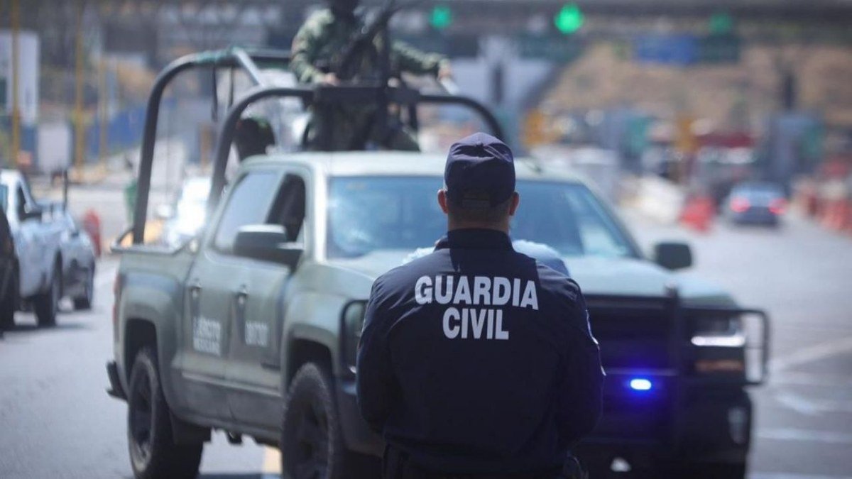 A Michoacán Guardia Civil officer stands in front of a Mexican Army pickup truck with a soldier manning a mounted gun