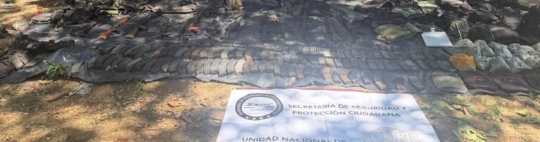 Rifle magazines, weapons and tactical gear laid out on a tarp beside a Mexican Security Ministry banner after arrests near Mazatlán, Sinaloa