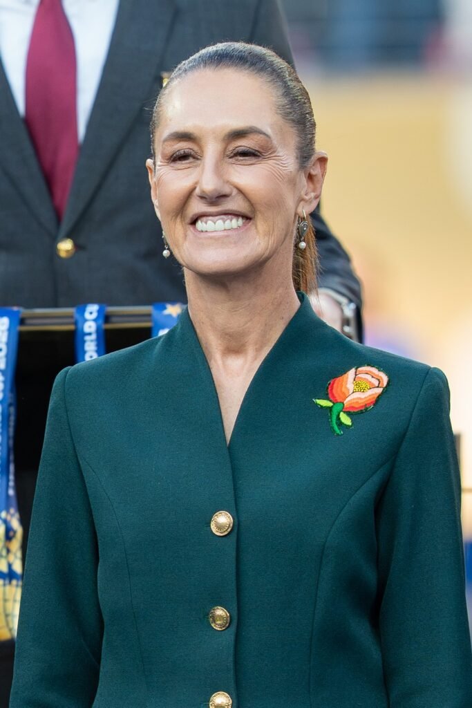 President Claudia Sheinbaum smiling in a green blazer at a public event