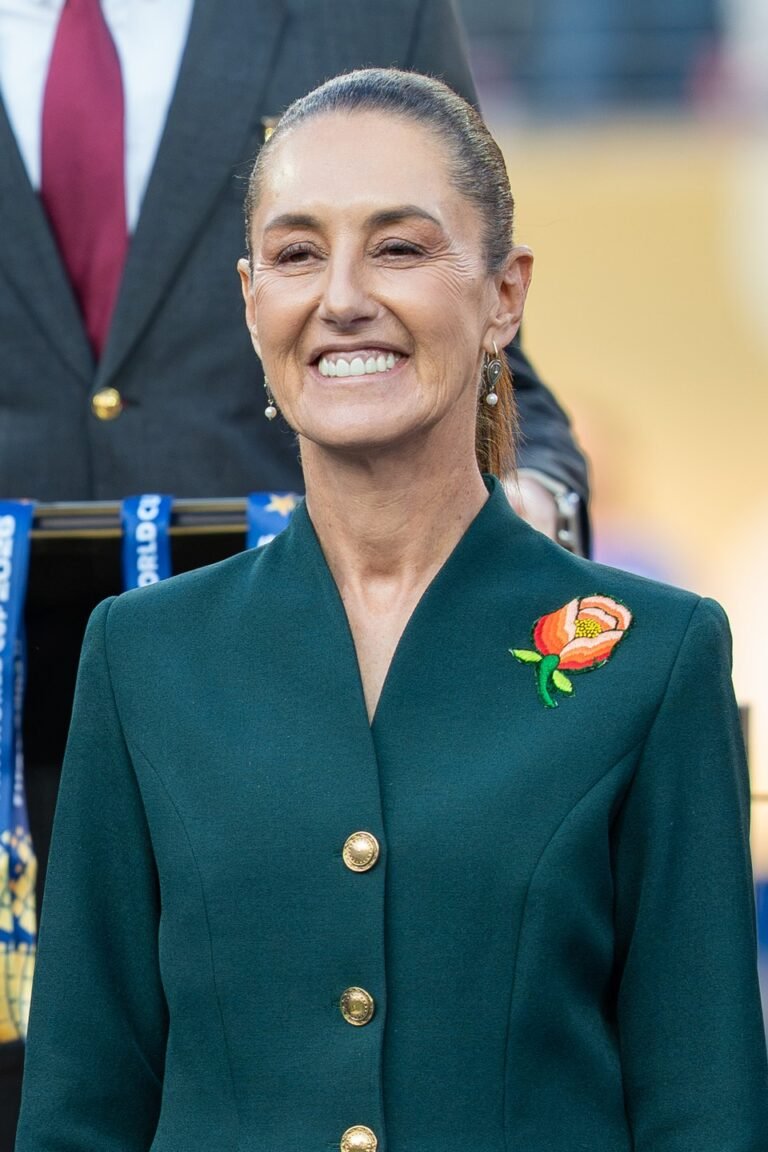 President Claudia Sheinbaum smiling in a green blazer at a public event