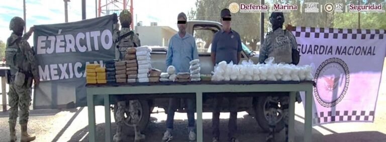 Two detained men with their faces blacked out stand behind a table of wrapped drug packages and plastic bags in front of a pickup truck, flanked by Mexican Army and National Guard troops and banners