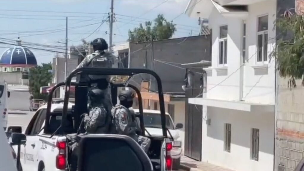 National Guard troops ride in the back of a patrol pickup on a residential street in Tecamachalco, Puebla, during the wake for the mayor's son.