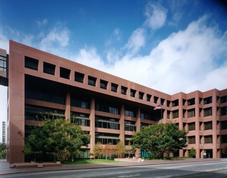 Reddish multi-story Edward J. Schwartz United States Courthouse building in San Diego with an American flag out front under a blue sky