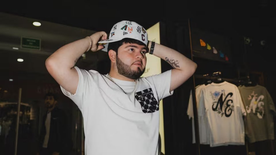 Singer Víctor Valverde in a white cap and T-shirt, adjusting his cap