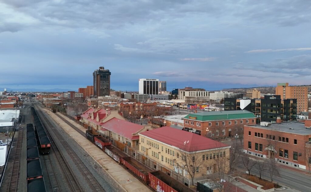 Downtown Billings, Montana, seen from above the railyard, with coal cars on the tracks, the historic red-roofed depot and the city's office towers behind
