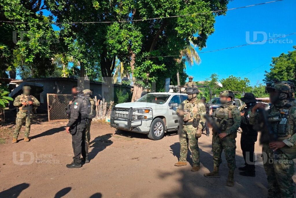 Mexican Marines and federal police in tactical gear stand on a dirt street beside a white Navy pickup outside a house in Laguna Colorada, Culiacán, during the Oct. 15 raids