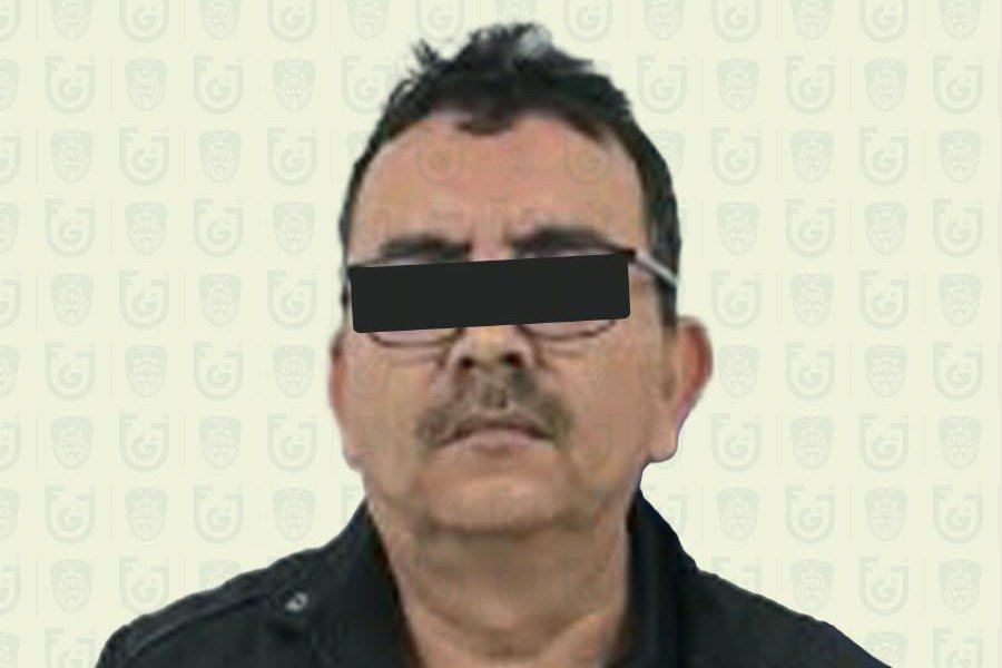 Official Mexico City prosecutors' photo of a middle-aged man with a mustache and glasses in a dark jacket, his eyes covered by a black bar, against a background printed with Fiscalía logos.