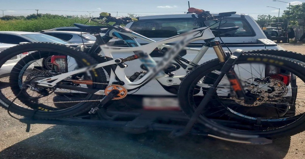 Two white mountain bikes on a rack mounted to the back of a white pickup truck, with the plate blurred
