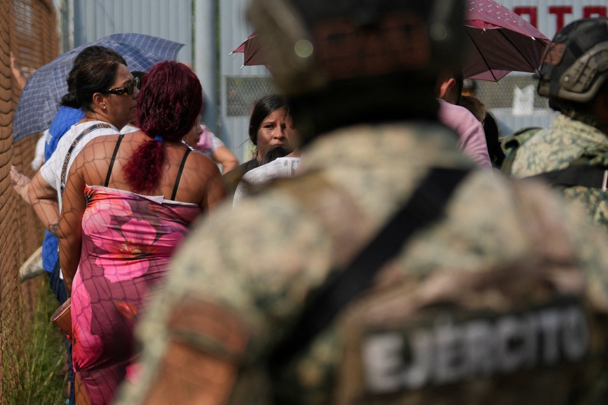 Relatives of inmates wait at the fence outside El Castillo prison in Mazatlán as a soldier stands in the foreground, Oct. 8, 2026