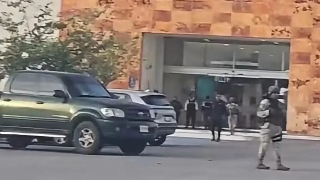 Soldiers and police stand outside the entrance of Plaza Galerías shopping mall in Mazatlán as an SUV drives past