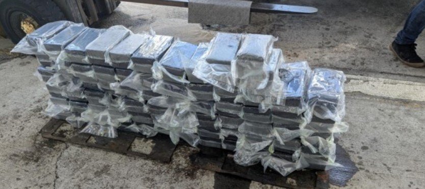 Dozens of wrapped brick-shaped packages stacked on a wooden pallet