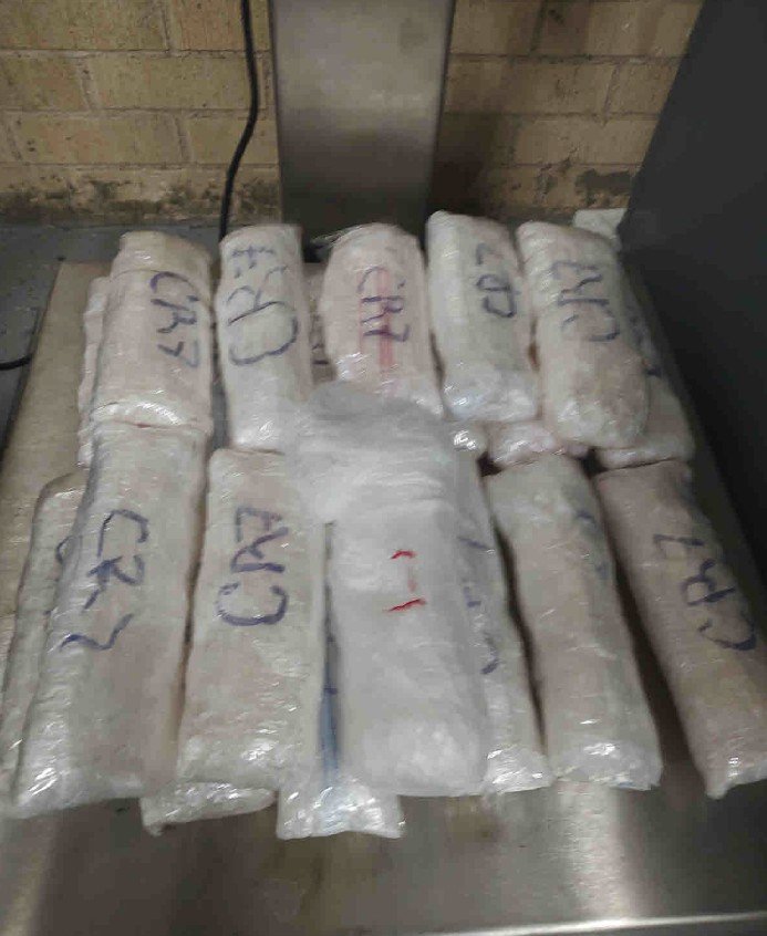 About a dozen plastic-wrapped packages of crystal methamphetamine marked in blue ink, stacked on a steel table