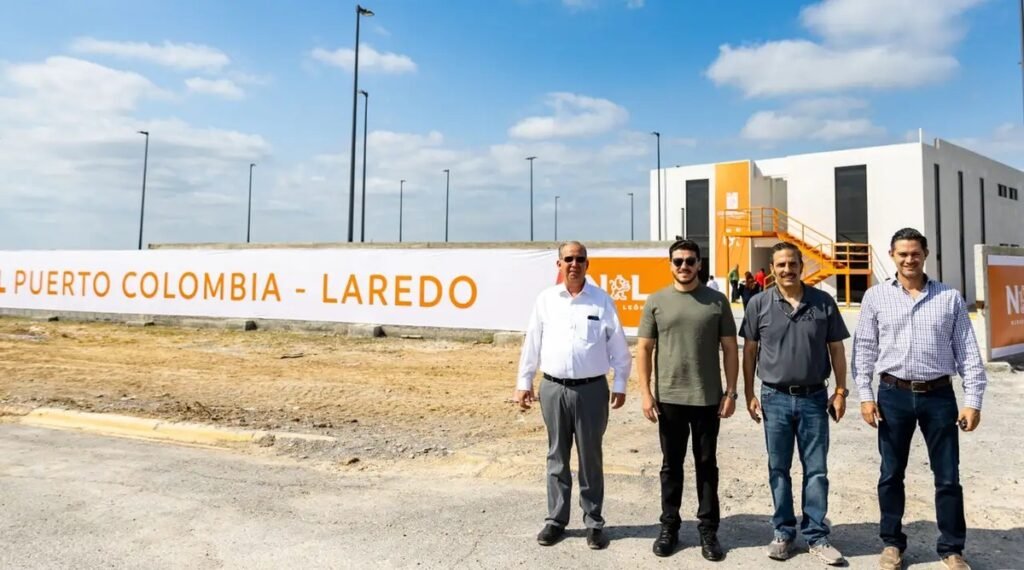 Nuevo León Gov. Samuel García, in a green T-shirt and sunglasses, stands with three men in front of a Puerto Colombia – Laredo banner and a new port building in Anáhuac, Nuevo León