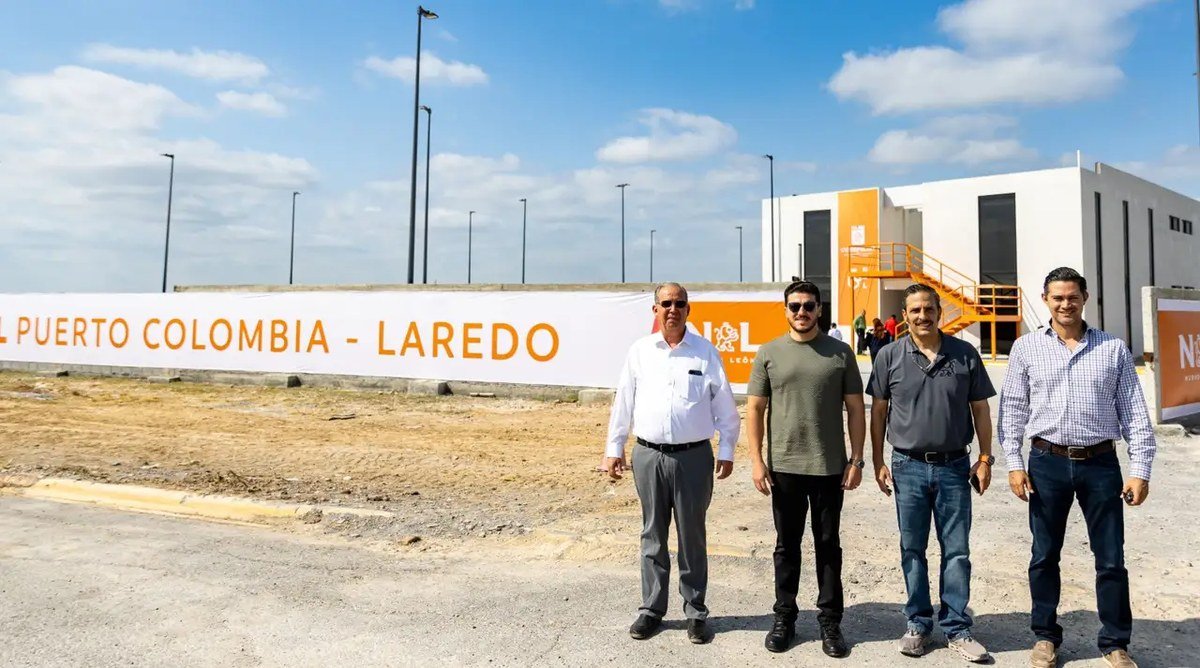 Nuevo León Gov. Samuel García, in a green T-shirt and sunglasses, stands with three men in front of a Puerto Colombia – Laredo banner and a new port building in Anáhuac, Nuevo León