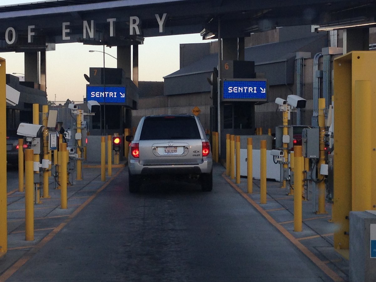 A silver SUV waits in a SENTRI lane under the Port of Entry canopy at the San Ysidro border crossing