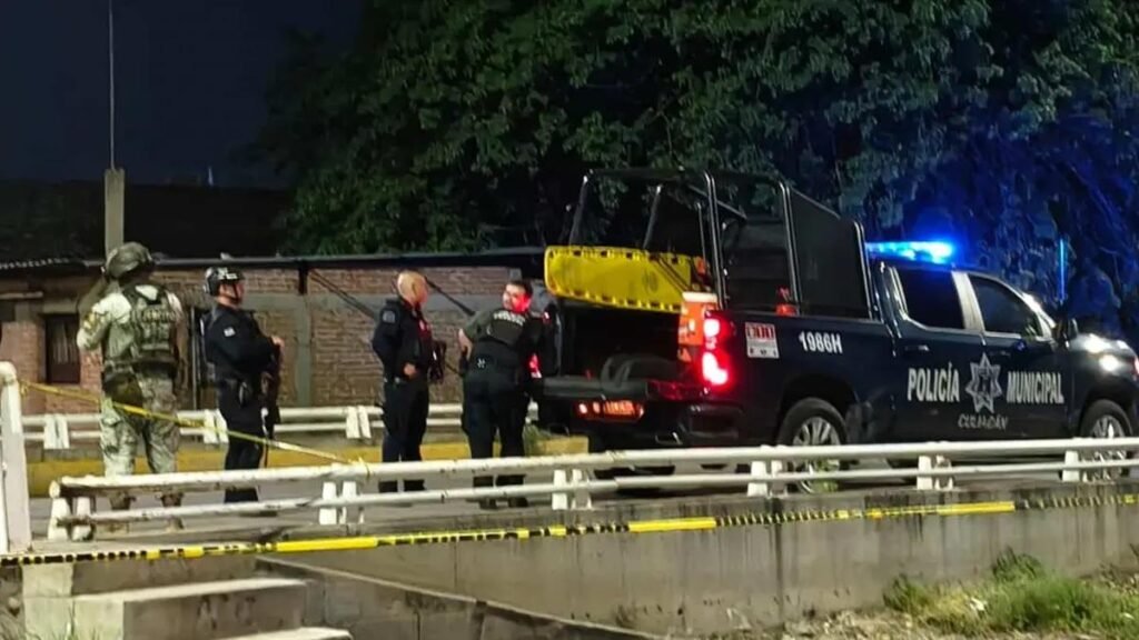 Mexican Army soldier and Culiacán municipal police officers beside a police pickup behind yellow tape at night