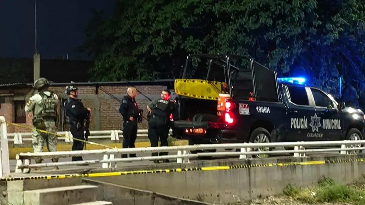 Mexican Army soldier and Culiacán municipal police officers beside a police pickup behind yellow tape at night