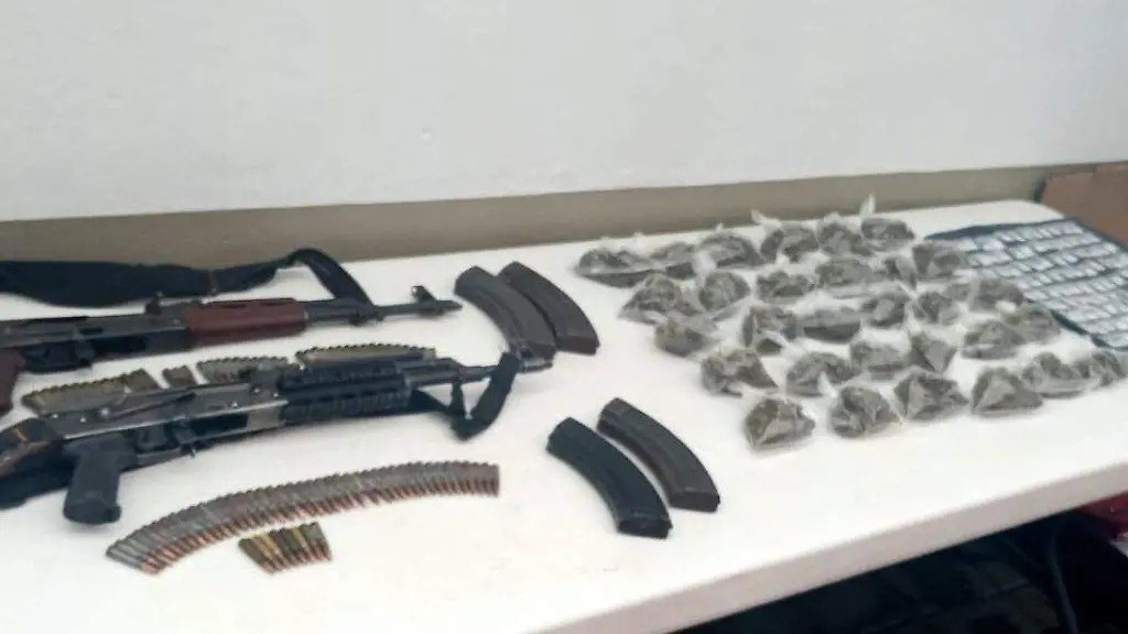 Two AK-pattern rifles, magazines, cartridges and dozens of small bags of suspected drugs laid out on a table